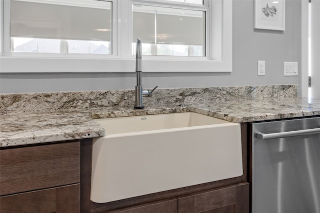 6318 Rapids Ridge Rd NE, Cedar Rapids, IA 52411 - kitchen view of stainless steel dishwasher, a sink, dark brown cabinetry, and light stone countertops