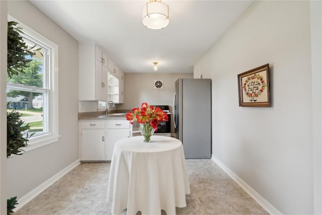 1252 29th St, Cedar Rapids, IA 52402 - kitchen featuring freestanding refrigerator, a sink, white cabinets, baseboards, and light countertops