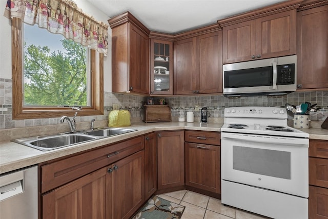 4427 J St SW, Cedar Rapids, IA 52404 - kitchen with appliances with stainless steel finishes, a sink, light countertops, decorative backsplash, and glass insert cabinets