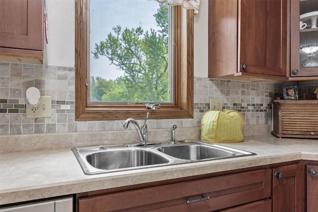4427 J St SW, Cedar Rapids, IA 52404 - kitchen featuring a sink, light countertops, glass insert cabinets, brown cabinetry, and decorative backsplash