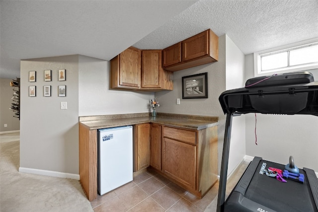 2985 4th St, Marion, IA 52302 - kitchen featuring refrigerator, brown cabinets, baseboards, a textured ceiling, and dark countertops