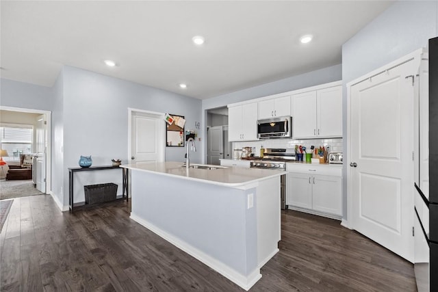 2890 Meadow Ct, Hiawatha, IA 52233 - kitchen with appliances with stainless steel finishes, a sink, a center island with sink, dark wood finished floors, and recessed lighting