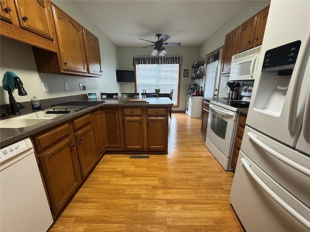 4610 Westchester Dr NE Unit A, Cedar Rapids, IA 52402 - kitchen featuring white appliances, a sink, light wood-style flooring, a peninsula, and ceiling fan