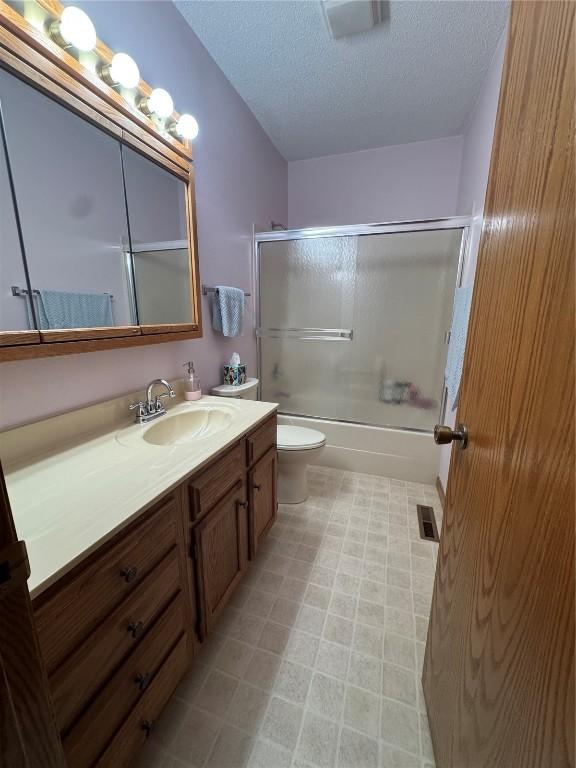 4610 Westchester Dr NE Unit A, Cedar Rapids, IA 52402 - full bath featuring vanity, a textured ceiling, toilet, and bath / shower combo with glass door