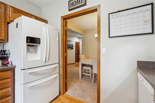 4610 Westchester Dr NE Unit A, Cedar Rapids, IA 52402 - kitchen with white refrigerator with ice dispenser, dark countertops, brown cabinetry, and light wood-style flooring