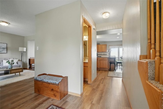 7025 Walden Rd NE, Cedar Rapids, IA 52402 - corridor featuring light wood finished floors, baseboards, and a textured ceiling