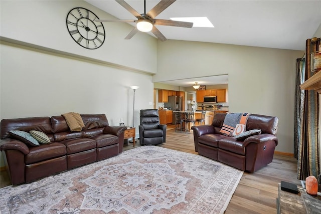 7025 Walden Rd NE, Cedar Rapids, IA 52402 - living room featuring light wood-type flooring, a skylight, high vaulted ceiling, ceiling fan, and baseboards