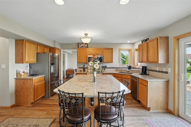 7025 Walden Rd NE, Cedar Rapids, IA 52402 - kitchen with appliances with stainless steel finishes, light wood-type flooring, a center island, light stone countertops, and recessed lighting