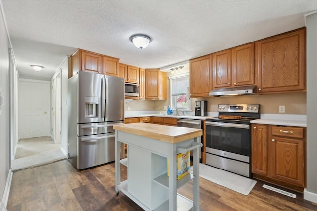 1026 Eisenhower Rd, Hiawatha, IA 52233 - kitchen featuring stainless steel appliances, under cabinet range hood, dark wood-style floors, open shelves, and a textured ceiling