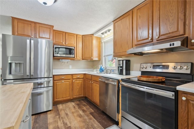 1026 Eisenhower Rd, Hiawatha, IA 52233 - kitchen with stainless steel appliances, under cabinet range hood, a sink, dark wood-type flooring, and a textured ceiling