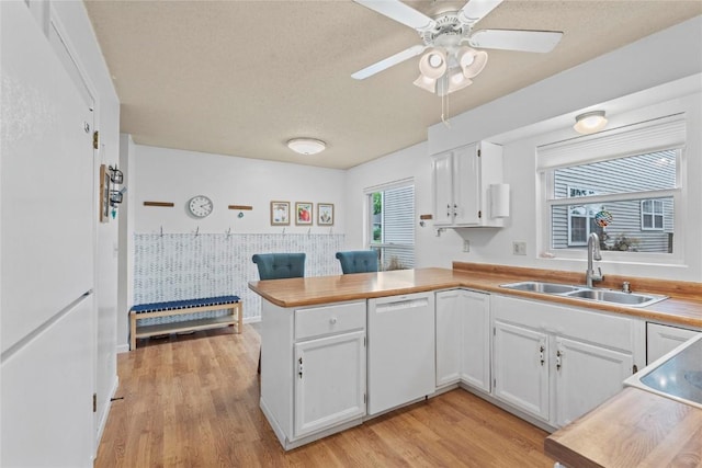 6813 Terrazzo Dr NW, Cedar Rapids, IA 52405 - kitchen with white dishwasher, a sink, a peninsula, white cabinets, and light wood-style floors