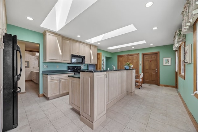 4324 C Ave NE, Cedar Rapids, IA 52402 - kitchen with black appliances, a skylight, dark countertops, light tile patterned floors, and light brown cabinets
