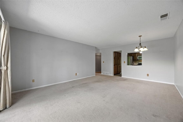 2131 1st Ave SE Unit 116, Cedar Rapids, IA 52403 - unfurnished living room with a chandelier, carpet floors, baseboards, and a textured ceiling