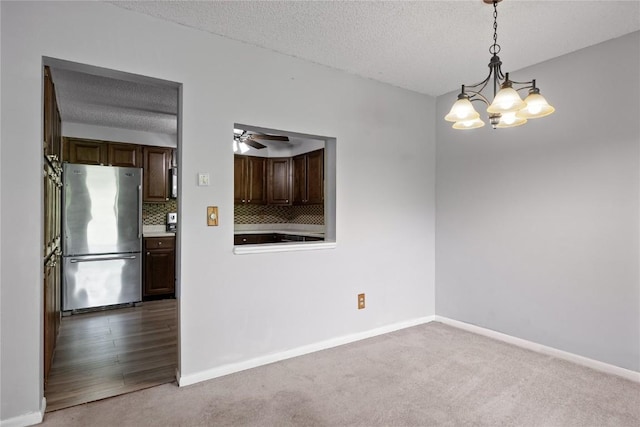 2131 1st Ave SE Unit 116, Cedar Rapids, IA 52403 - empty room with carpet, a textured ceiling, a chandelier, and baseboards