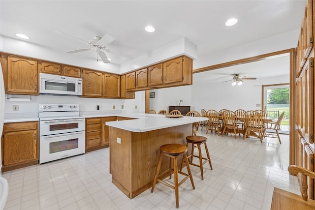 1782 Baker Ave, West Branch, IA 52358 - kitchen with white appliances, ceiling fan, a kitchen breakfast bar, brown cabinets, and recessed lighting