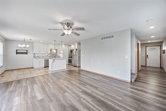 2273 Holiday Rd, Coralville, IA 52241 - unfurnished living room featuring light wood finished floors, a chandelier, ceiling fan, baseboards, and recessed lighting