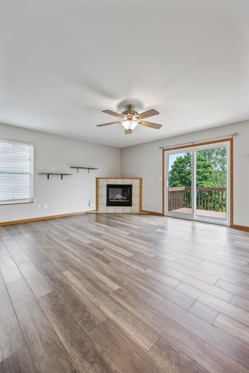 2273 Holiday Rd, Coralville, IA 52241 - unfurnished living room featuring ceiling fan, wood finished floors, baseboards, and a tiled fireplace
