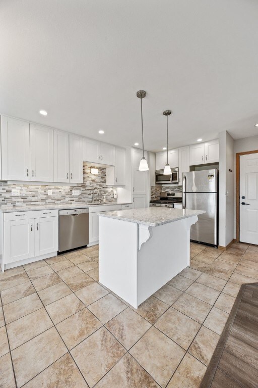 2273 Holiday Rd, Coralville, IA 52241 - kitchen featuring appliances with stainless steel finishes, decorative backsplash, white cabinetry, recessed lighting, and light tile patterned floors