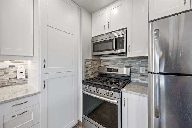 2273 Holiday Rd, Coralville, IA 52241 - kitchen with appliances with stainless steel finishes, white cabinetry, tasteful backsplash, and light stone counters