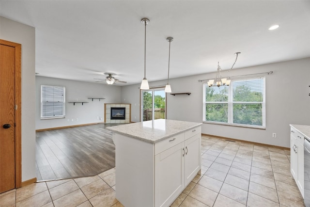 2273 Holiday Rd, Coralville, IA 52241 - kitchen featuring ceiling fan, a tiled fireplace, white cabinets, hanging light fixtures, and baseboards