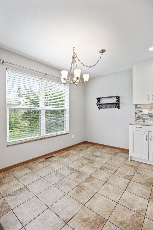 2273 Holiday Rd, Coralville, IA 52241 - unfurnished dining area with healthy amount of natural light, a chandelier, and baseboards