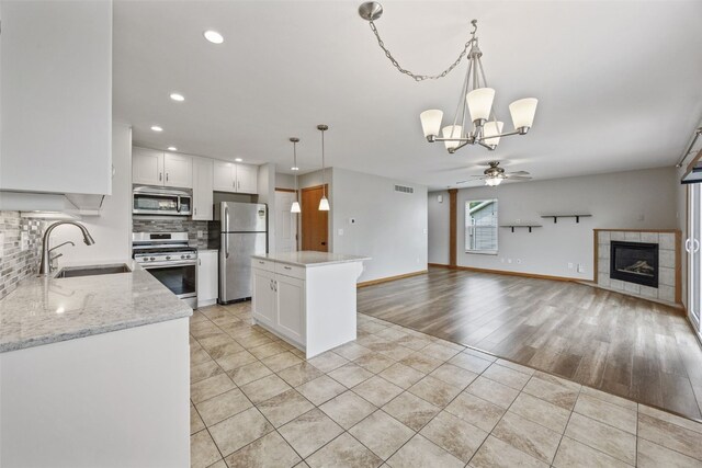 2273 Holiday Rd, Coralville, IA 52241 - kitchen with stainless steel appliances, a sink, a chandelier, a ceiling fan, and backsplash