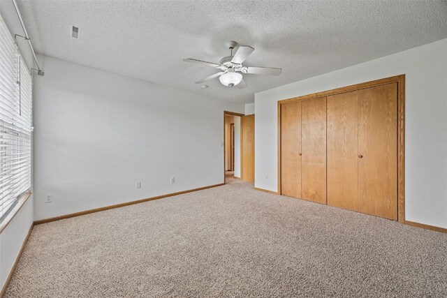 2273 Holiday Rd, Coralville, IA 52241 - unfurnished bedroom with light carpet, a closet, baseboards, a ceiling fan, and a textured ceiling