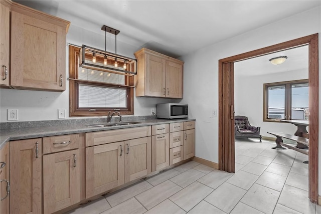 3152 66th St, Shellsburg, IA 52332 - kitchen with stainless steel microwave, a sink, light brown cabinets, hanging light fixtures, and light tile patterned flooring