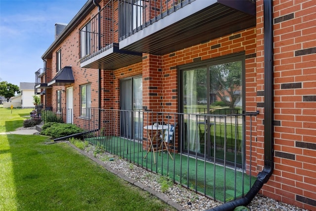 849 Kerry Ln SE Unit 49, Cedar Rapids, IA 52403 - view of exterior entry featuring brick siding, a balcony, and a yard