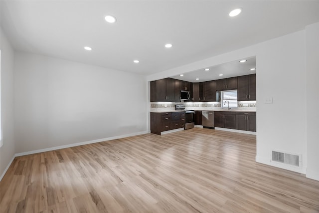 5208 Gordon Ave NW, Cedar Rapids, IA 52405 - kitchen with appliances with stainless steel finishes, light countertops, dark brown cabinetry, light wood finished floors, and recessed lighting