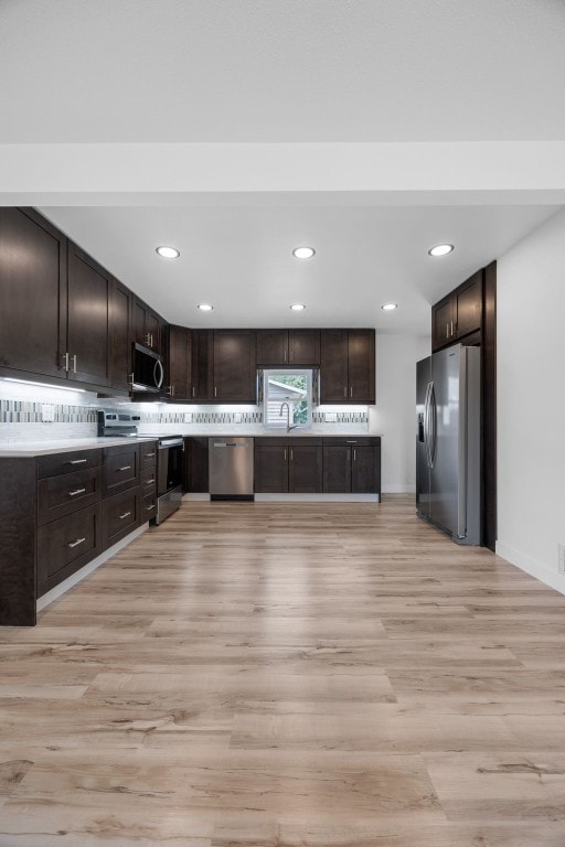 5208 Gordon Ave NW, Cedar Rapids, IA 52405 - kitchen with appliances with stainless steel finishes, light wood-type flooring, dark brown cabinetry, a sink, and recessed lighting