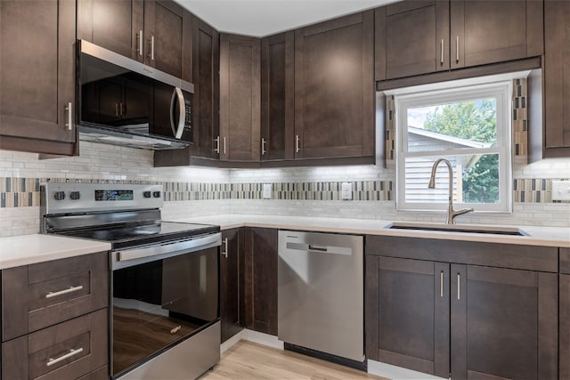 5208 Gordon Ave NW, Cedar Rapids, IA 52405 - kitchen with stainless steel appliances, a sink, dark brown cabinetry, and tasteful backsplash