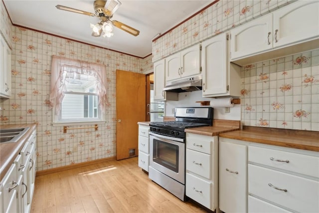 2241 Williams Blvd SW, Cedar Rapids, IA 52404 - kitchen featuring stainless steel gas range, under cabinet range hood, wallpapered walls, light wood-style floors, and white cabinetry
