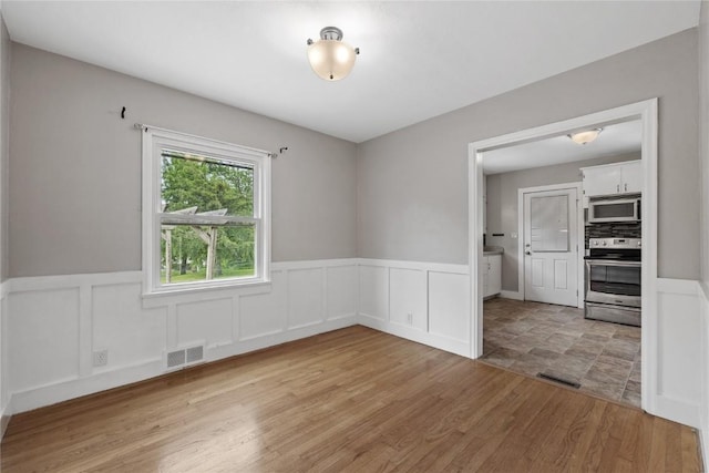 2820 12th Ave SW, Cedar Rapids, IA 52404 - empty room with a wainscoted wall, light wood-type flooring, and a decorative wall