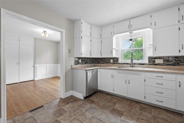 2820 12th Ave SW, Cedar Rapids, IA 52404 - kitchen with dishwasher, a sink, backsplash, white cabinets, and a wainscoted wall