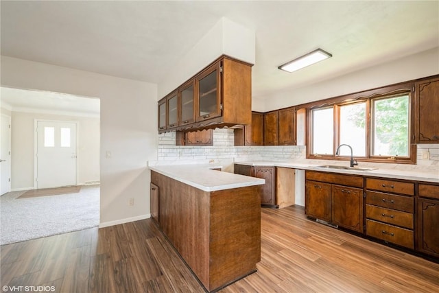 3099 27th Ave, Marion, IA 52302 - kitchen featuring a sink, wood finished floors, glass insert cabinets, decorative backsplash, and light countertops