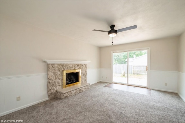 3099 27th Ave, Marion, IA 52302 - unfurnished living room with a ceiling fan, carpet flooring, a stone fireplace, and wainscoting