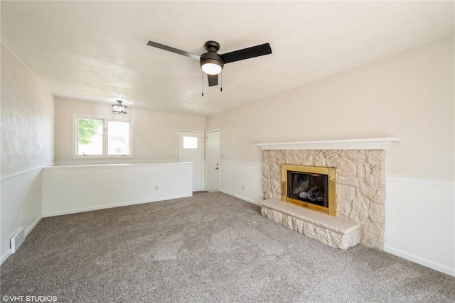 3099 27th Ave, Marion, IA 52302 - unfurnished living room featuring ceiling fan, carpet, a wainscoted wall, and a stone fireplace