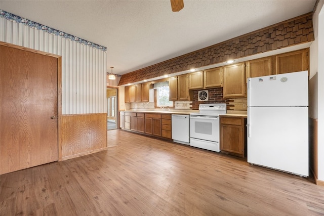 502 5th Ave, Clarence, IA 52216 - kitchen with white appliances, light wood-style flooring, light countertops, brown cabinetry, and decorative backsplash