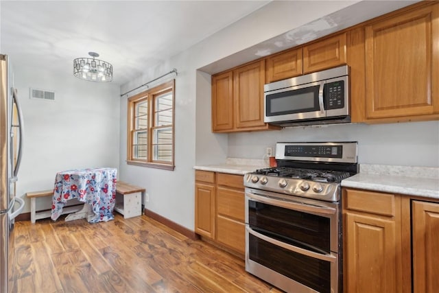 722 47th Ave, Amana, IA 52203 - kitchen with stainless steel appliances, light countertops, wood finished floors, and a chandelier