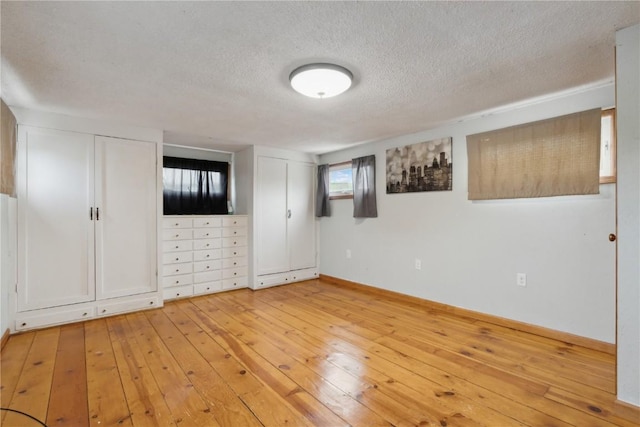 722 47th Ave, Amana, IA 52203 - unfurnished bedroom with multiple closets, light wood-style flooring, a textured ceiling, and baseboards