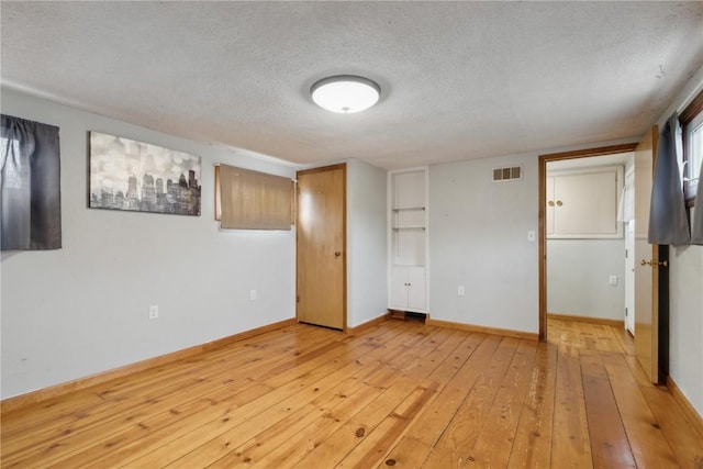 722 47th Ave, Amana, IA 52203 - unfurnished bedroom with a textured ceiling, light wood-type flooring, and baseboards