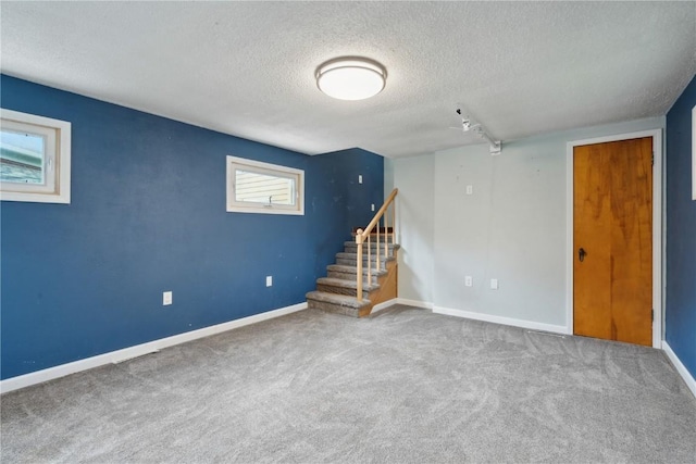 722 47th Ave, Amana, IA 52203 - below grade area with a textured ceiling, carpet floors, stairs, baseboards, and rail lighting