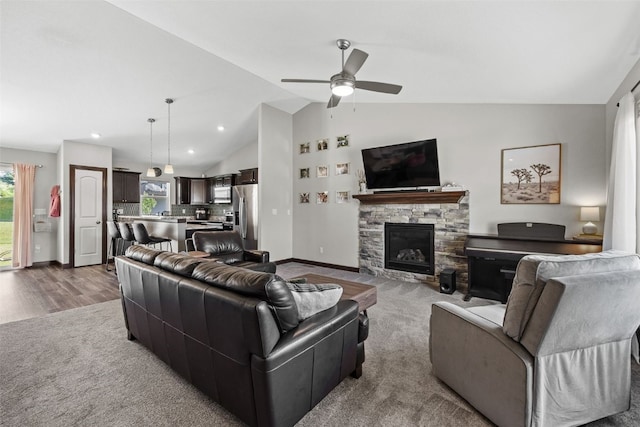 2106 Shady Grove Rd SW, Cedar Rapids, IA 52404 - carpeted living room with vaulted ceiling, ceiling fan, a stone fireplace, baseboards, and recessed lighting