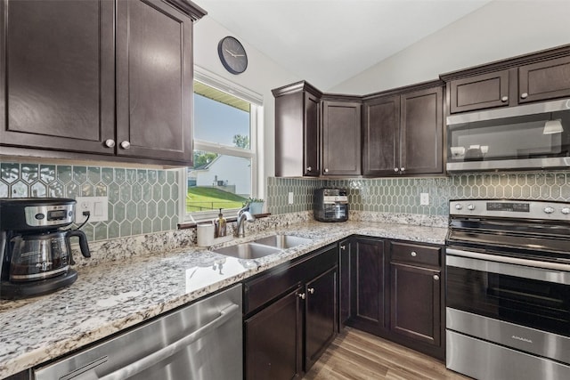2106 Shady Grove Rd SW, Cedar Rapids, IA 52404 - kitchen featuring appliances with stainless steel finishes, a sink, vaulted ceiling, dark brown cabinetry, and light wood finished floors
