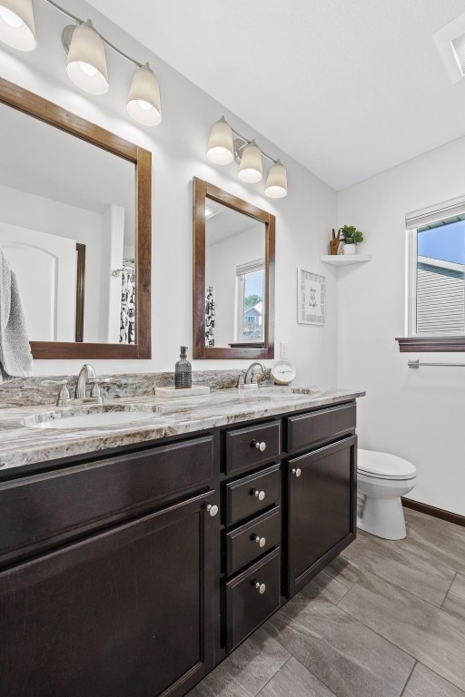 2106 Shady Grove Rd SW, Cedar Rapids, IA 52404 - bathroom featuring double vanity, toilet, healthy amount of natural light, and wood finished floors