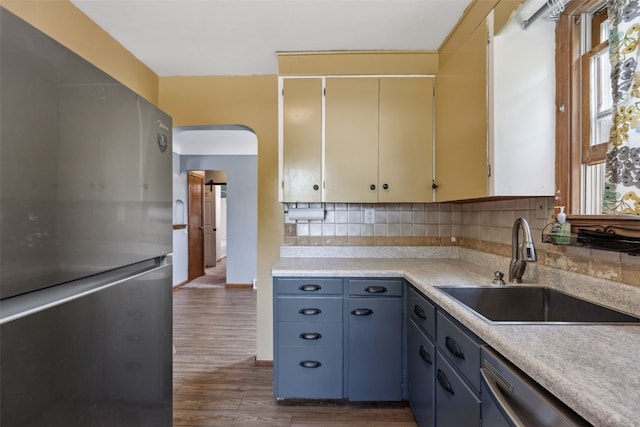 331 36th St NE, Cedar Rapids, IA 52402 - kitchen with stainless steel appliances, a sink, arched walkways, tasteful backsplash, and wood finished floors