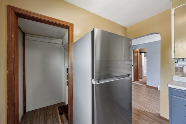 331 36th St NE, Cedar Rapids, IA 52402 - kitchen with freestanding refrigerator, wood finished floors, light countertops, arched walkways, and baseboards
