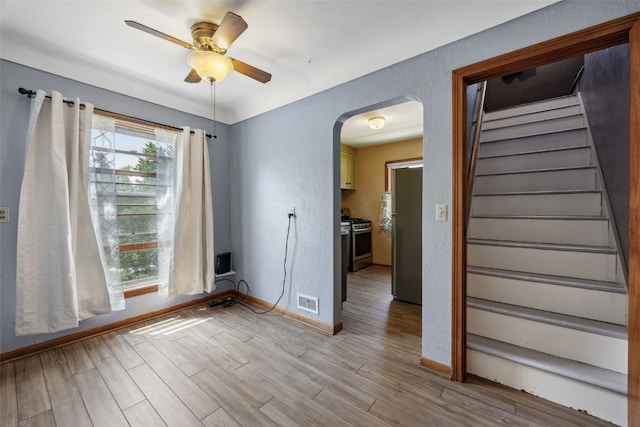 331 36th St NE, Cedar Rapids, IA 52402 - empty room featuring arched walkways, light wood finished floors, ceiling fan, stairs, and baseboards
