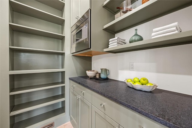 679 Allison Way, Iowa City, IA 52245 - kitchen with open shelves, stainless steel microwave, dark stone countertops, and white cabinets